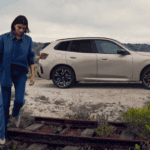 A person walks away from a bronze 2026 BMW X3
