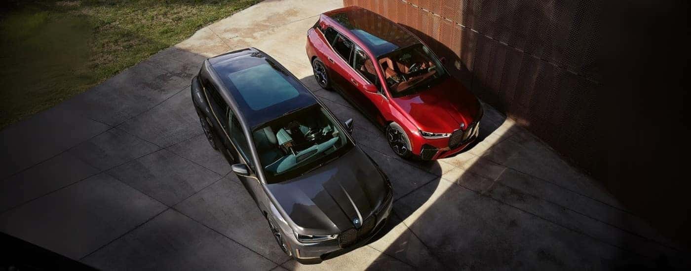 A red and a grey 2022 BMW iX parked side by side in a driveway