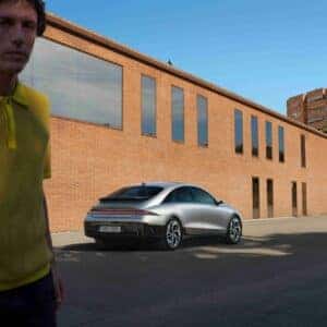rear right quarter view of a car with a man in yellow shirt