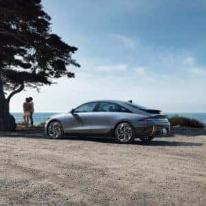 A Hyundai Ioniq 6 parked near a beachside road, displaying its sloping roofline, rear LED taillights, and sporty stance.