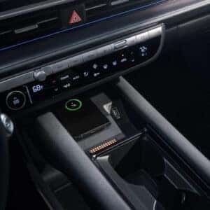 A close-up of the Hyundai Ioniq 6’s center console, featuring a wireless charging pad with a smartphone displaying a charging status.