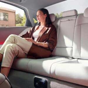 A woman comfortably seated in the rear of the Hyundai Ioniq 6, enjoying spacious legroom and red ambient lighting.