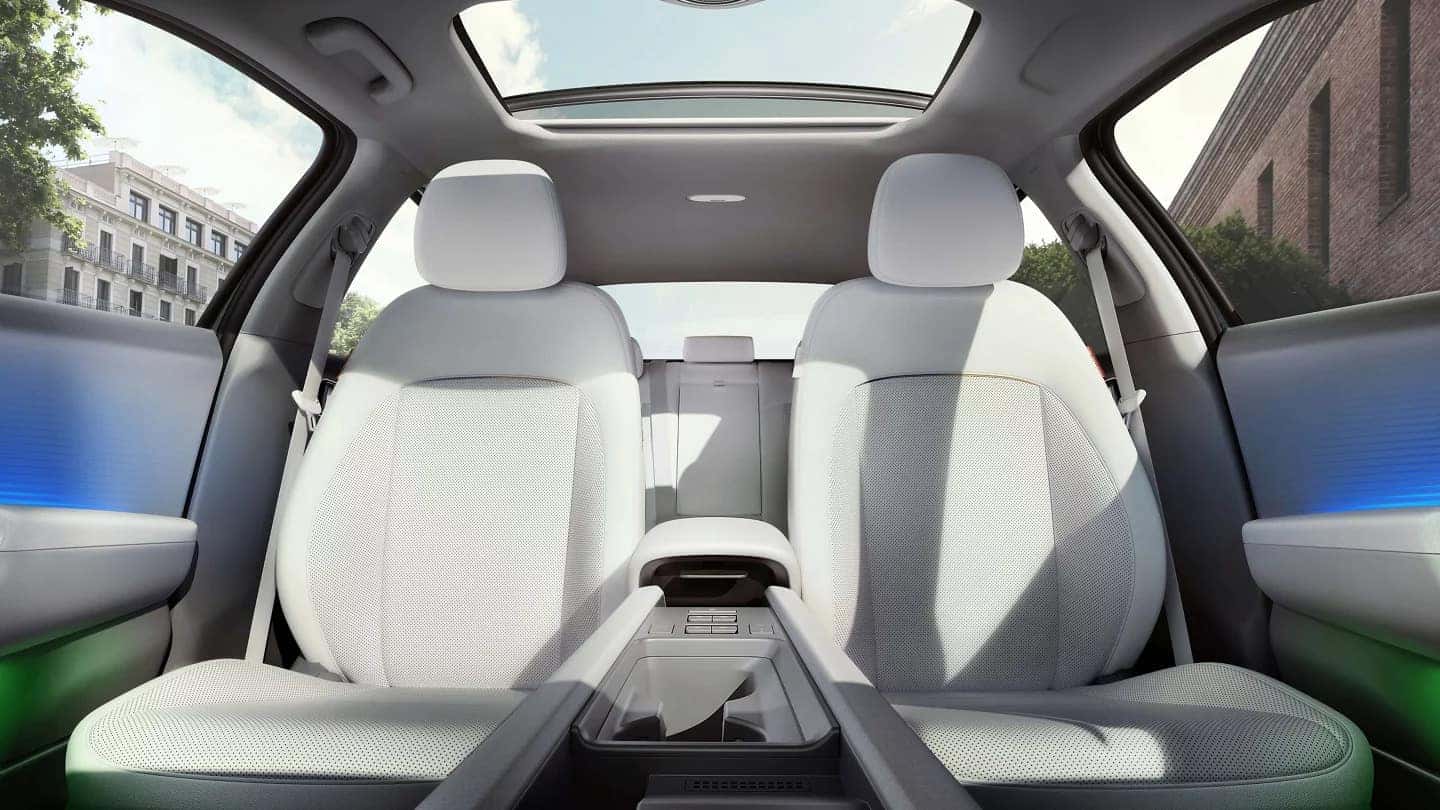 A spacious and modern interior of the Hyundai Ioniq 6, showcasing the front seats with light-colored upholstery and a panoramic sunroof.