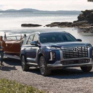 2023 Hyundai Palisade towing a classic boat at a waterfront location.