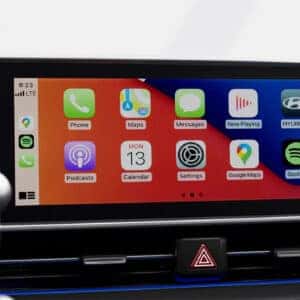 Close-up of the Hyundai IONIQ 6 infotainment screen with Apple CarPlay, showing various app icons such as Google Maps, Spotify, and Podcasts.