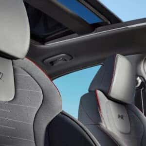 Front seats of the 2024 Hyundai Sonata N Line, showcasing the N badging, red stitching, and a panoramic sunroof.