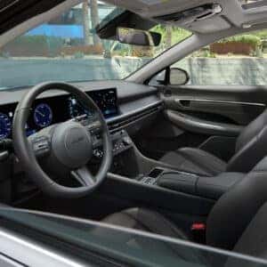 A wide-angle view of the cabin in the 2024 Hyundai Sonata Hybrid, featuring a fully digital driver display, touchscreen infotainment system, and premium black leather seats.