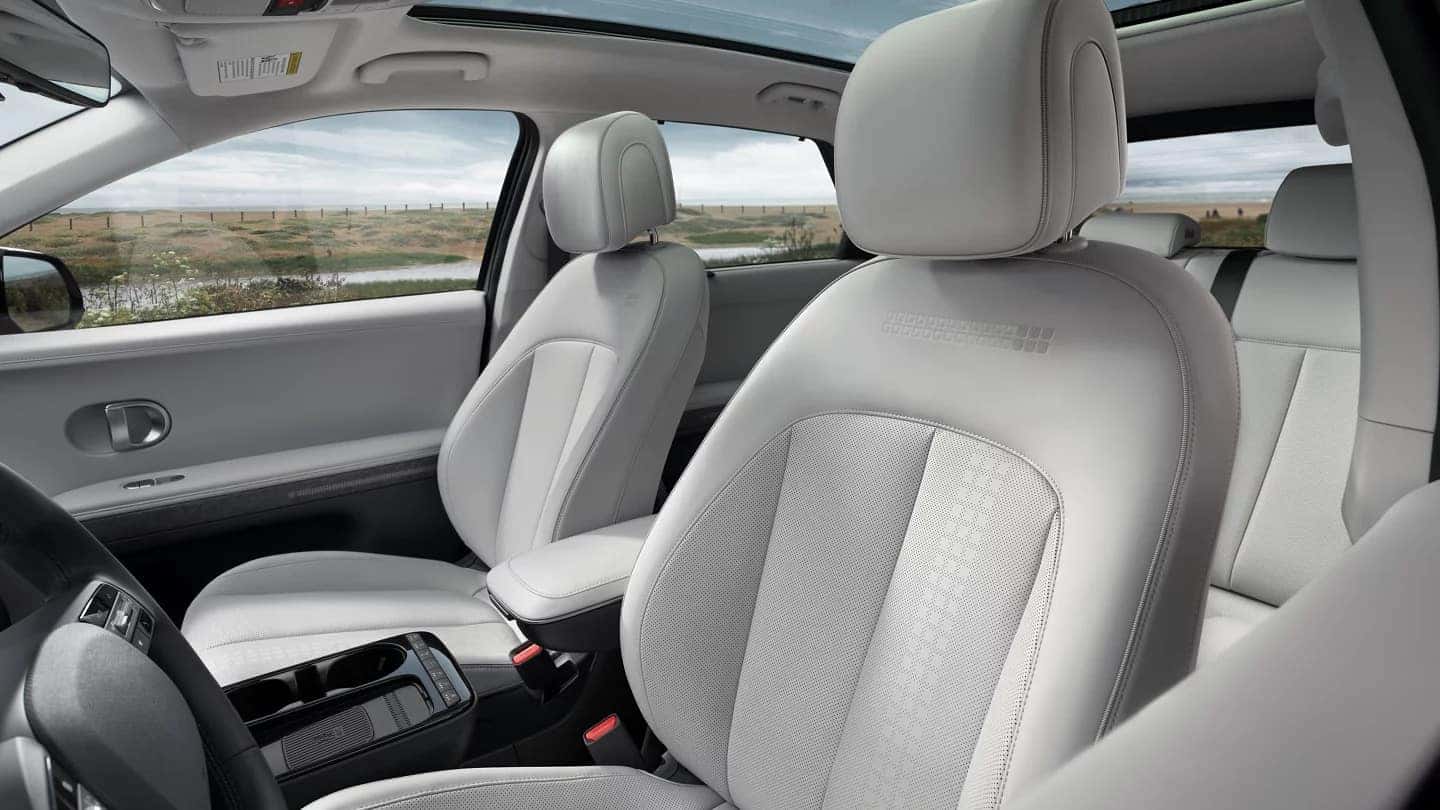 Front seats of the 2025 Hyundai Ioniq 5 with light-colored upholstery and a panoramic sunroof.