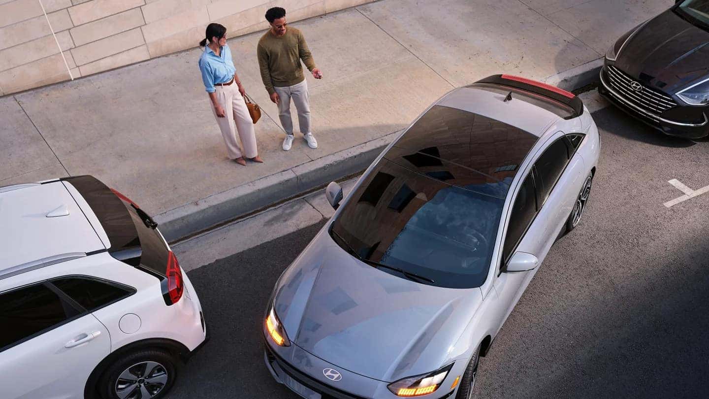 A Hyundai IONIQ 6 parked on the street as two people approach, highlighting the vehicle's sleek exterior design.