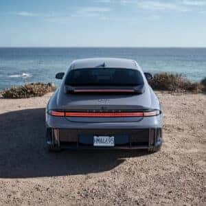 Rear view of a Hyundai IONIQ 6 parked on a scenic coastal area, featuring its unique taillight design and sloping roofline.