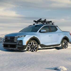 a blue santa cruz parked in snow overlooking white capped mountains
