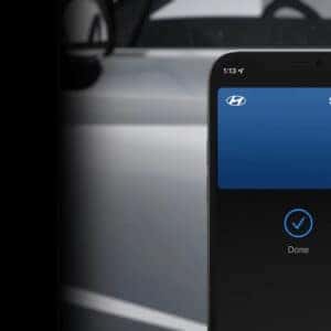 A smartphone showing a digital key confirmation screen for the Hyundai Sonata, with the car's side profile visible in the background.