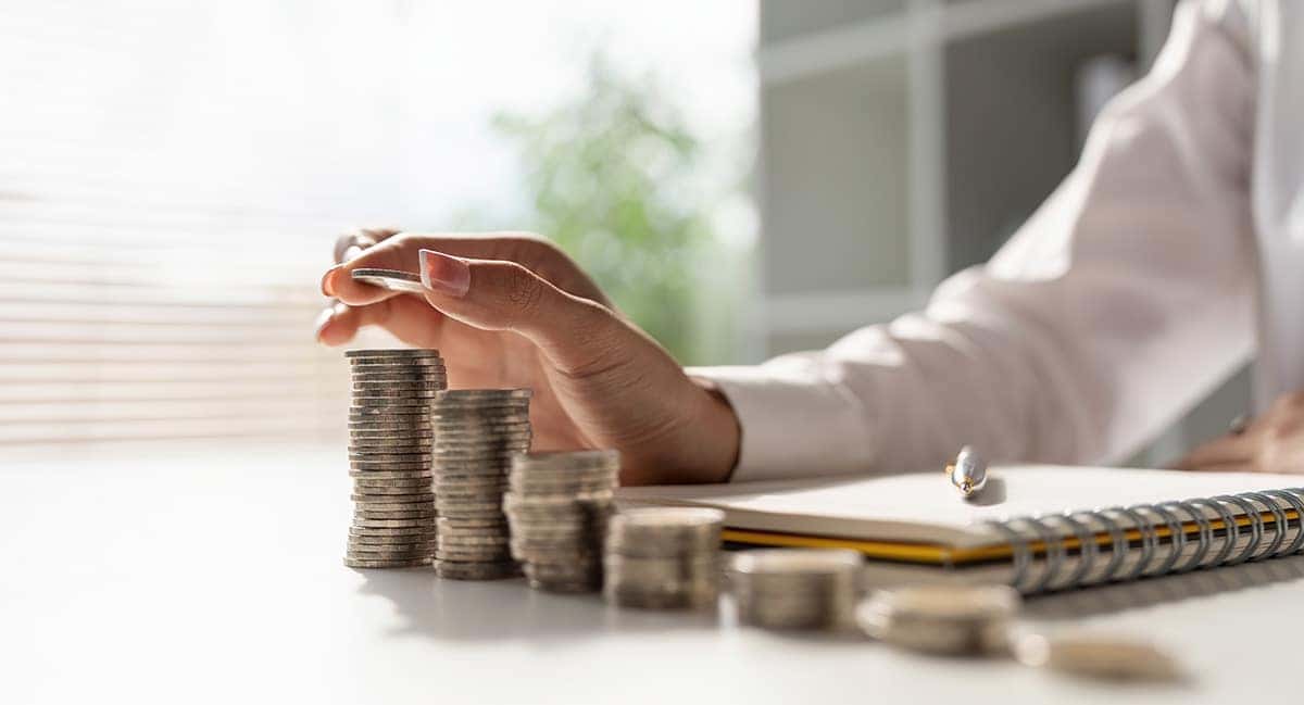 a person counting quarters stacked up with a pen and notebook 