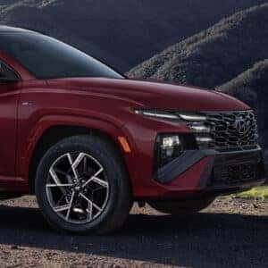 Front quarter view of a red 2025 Hyundai Tucson N Line in a mountainous setting, emphasizing its aggressive front fascia and distinctive wheel design.