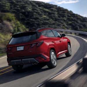 Dynamic shot of a red 2025 Hyundai Tucson driving on a mountain road