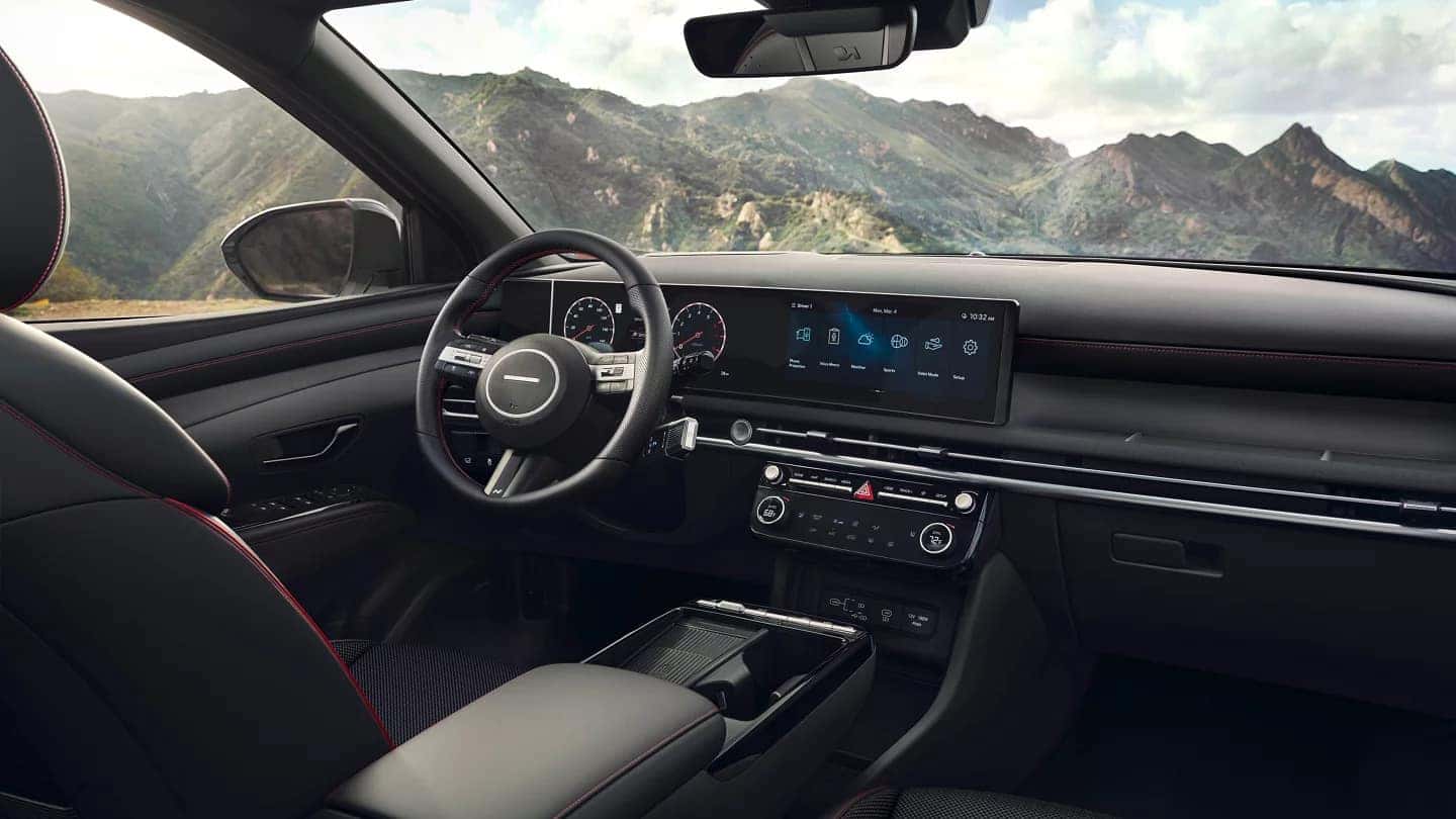 Wide-angle view of the 2025 Hyundai Tucson's interior dashboard, featuring dual 12.3-inch displays and a clean, modern design with physical climate controls.