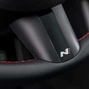 Close-up of a steering wheel in the 2025 Hyundai Tucson N Line, showing the N badge and red stitching details on black leather.