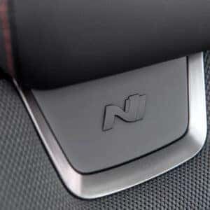 Close-up of an N Line badge on the headrest of the Tucson's sport seats, featuring the distinctive N logo on a metallic surface against black textured upholstery.