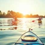 People kayak during sunset