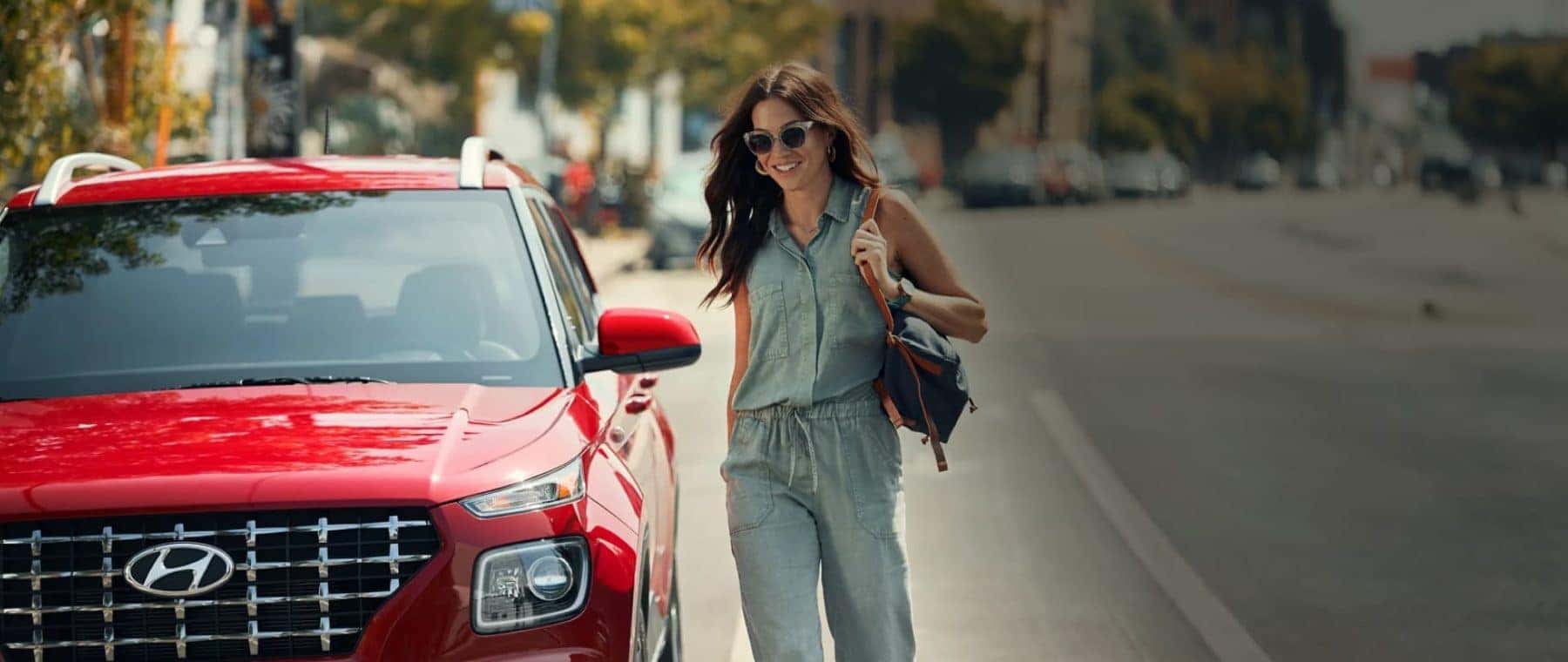 Woman walking next to a red Hyundai vehicle