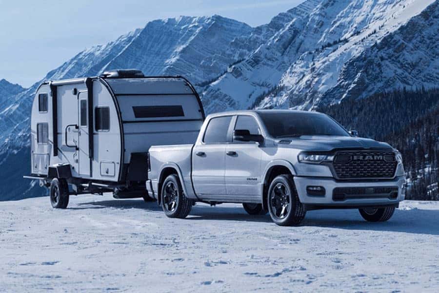 Ram 1500 towing camper in snowy mountain landscape