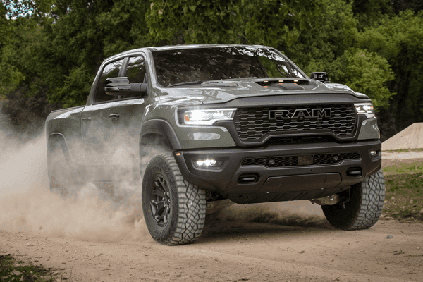 Grey Ram 1500 driving down dirt road three-quarter front view
