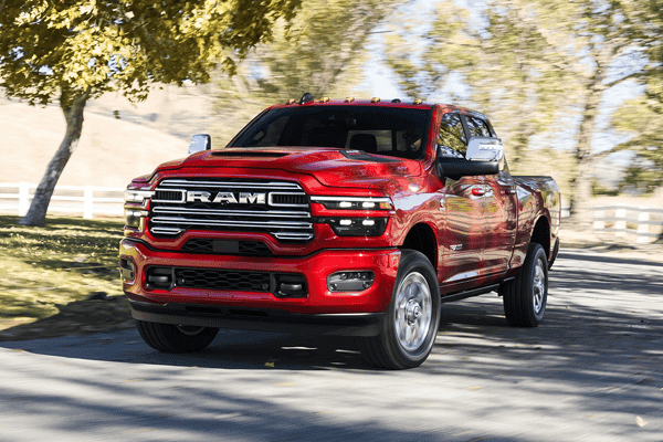 Red Ram 2500 pickup truck driving down a tree-lined street, front three-quarter view