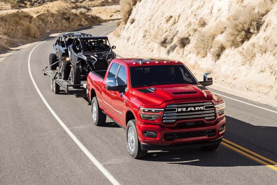 Red Ram 2500 towing 2 dune buggies on a two-lane road
