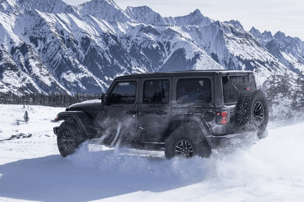 black jeep wrangler driving through snow