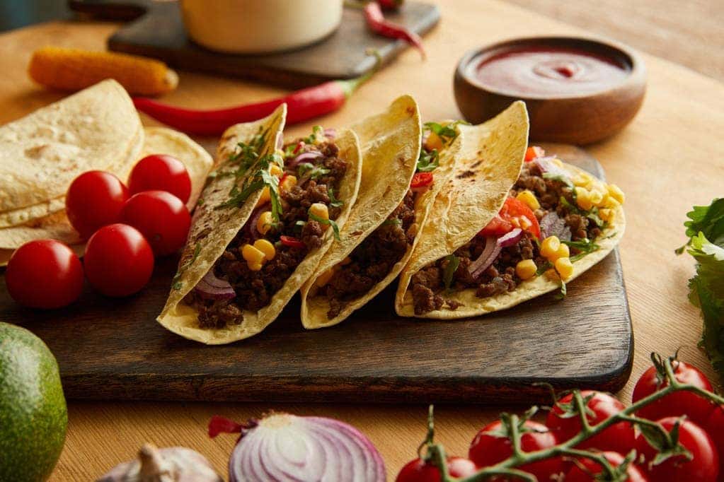 Tacos plated on a cutting board on a wooden table