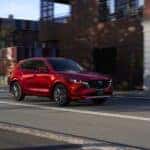 Red 2025 Mazda CX-5 driving down a road