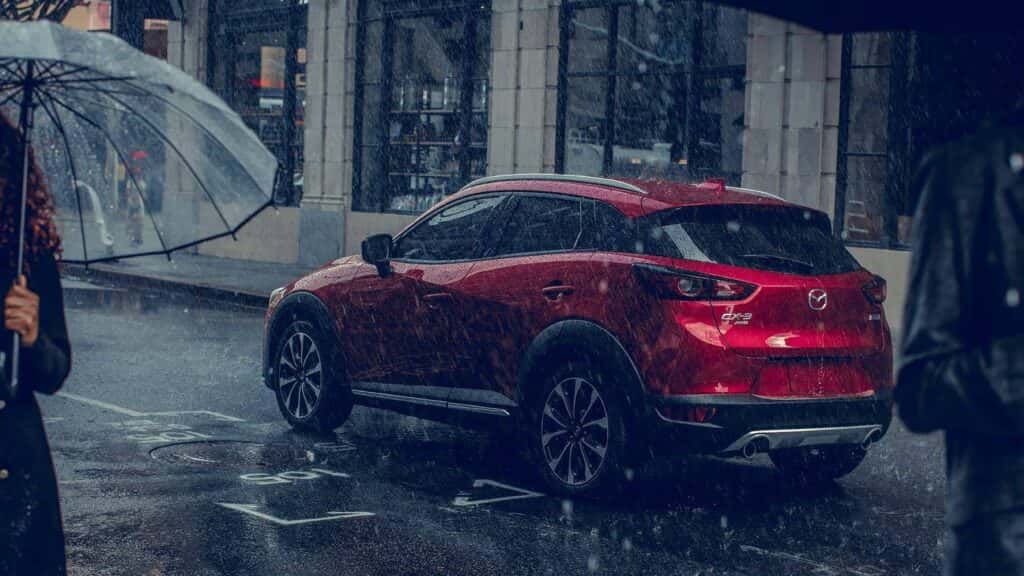 red mazda suv driving in the rain