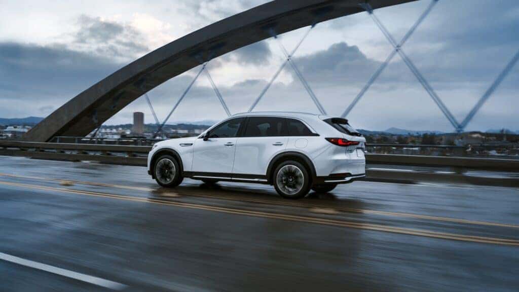 white 2026 cx-90 phev driving across a bridge