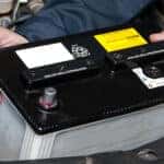 mechanic putting mazda car battery into engine area