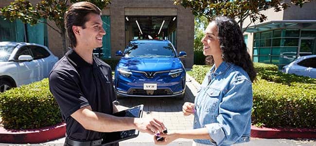 A VinFast employee handing a customer keys