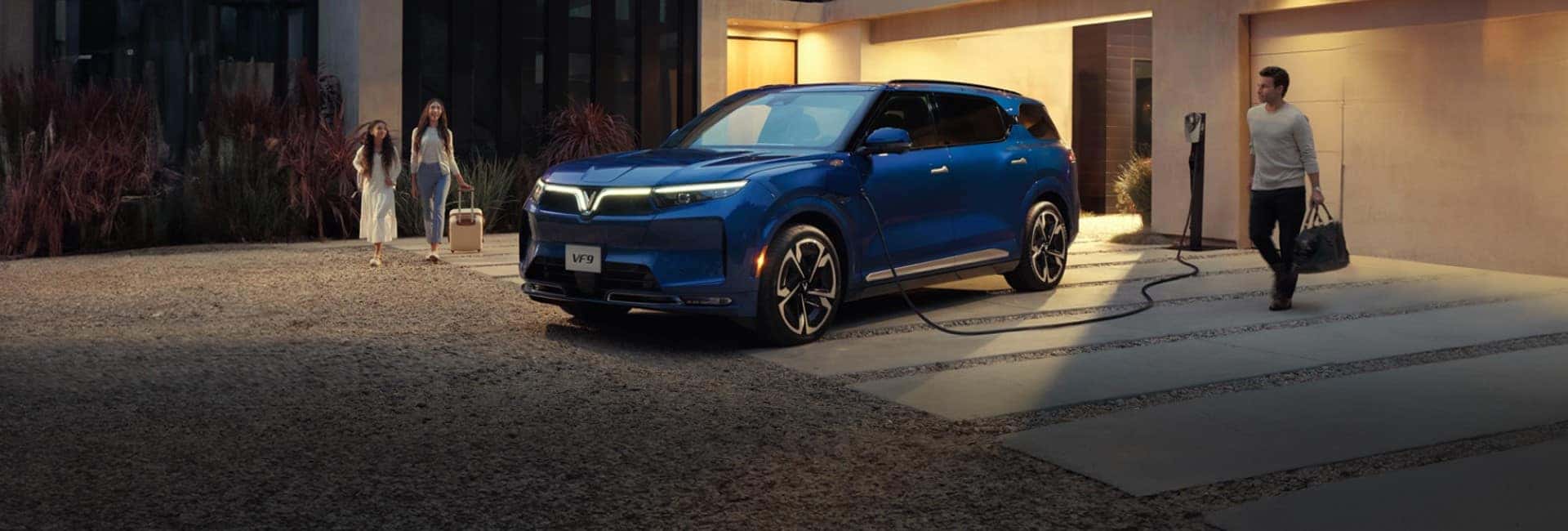 A blue VF 9 charging in a driveway